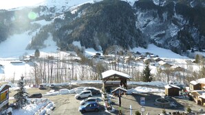 Ein verschneites Bergdorf mit Parkplatz, einem Holzgebäude mit schneebedecktem Dach und freiem Blick auf die Berge.