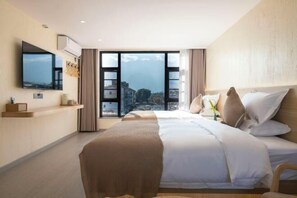 A modern hotel room with a large bed, a flat-screen TV, and a city view through the windows. - Dali twilight cang view light luxury inn (Dali)