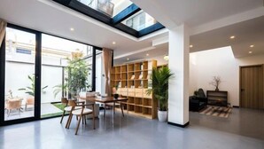 Un salon moderne comprenant un coin repas, une bibliothèque intégrée et une grande fenêtre donnant sur un jardin.