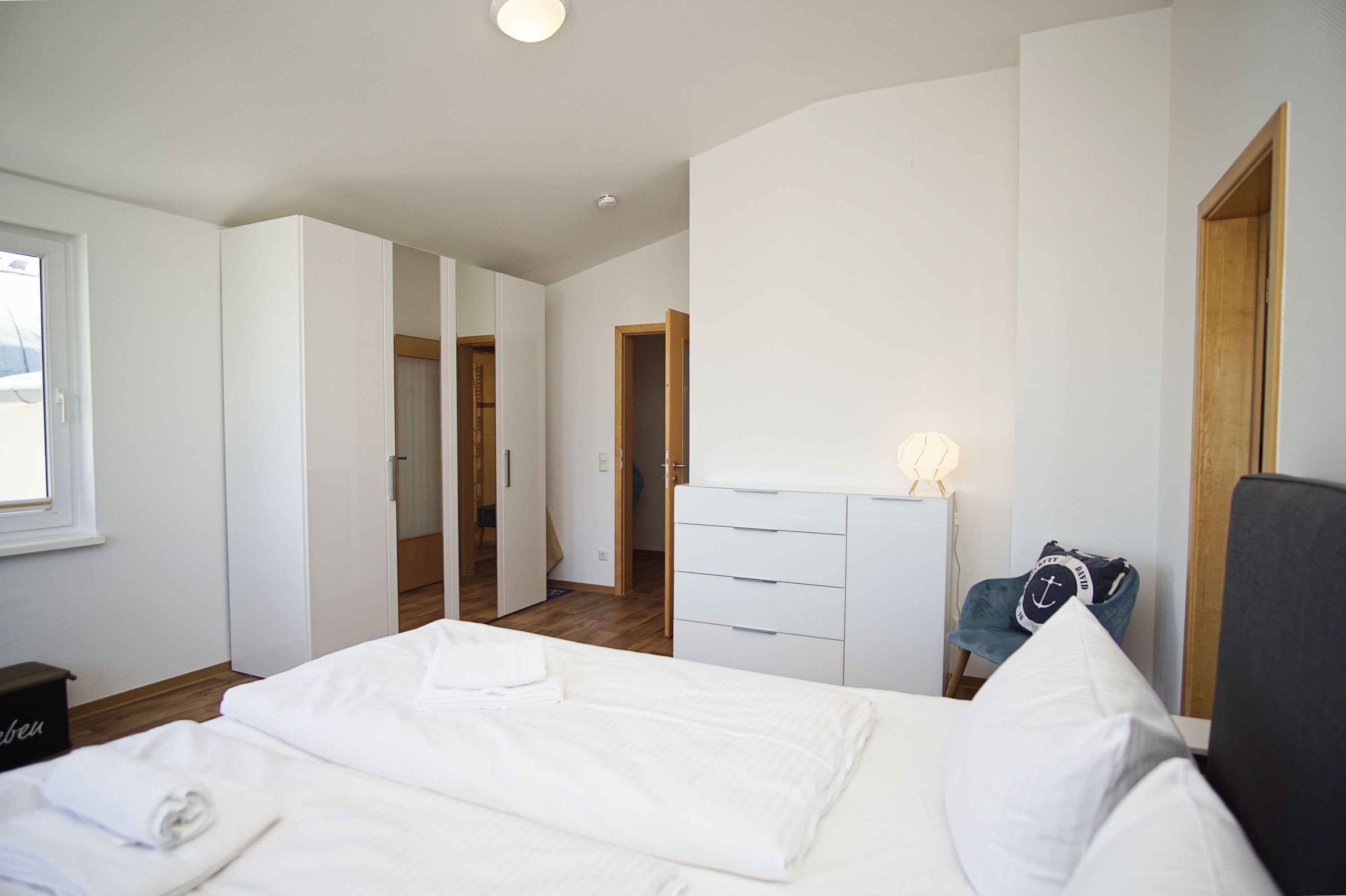 A bedroom with a bed, a dresser, a chair, and a window.