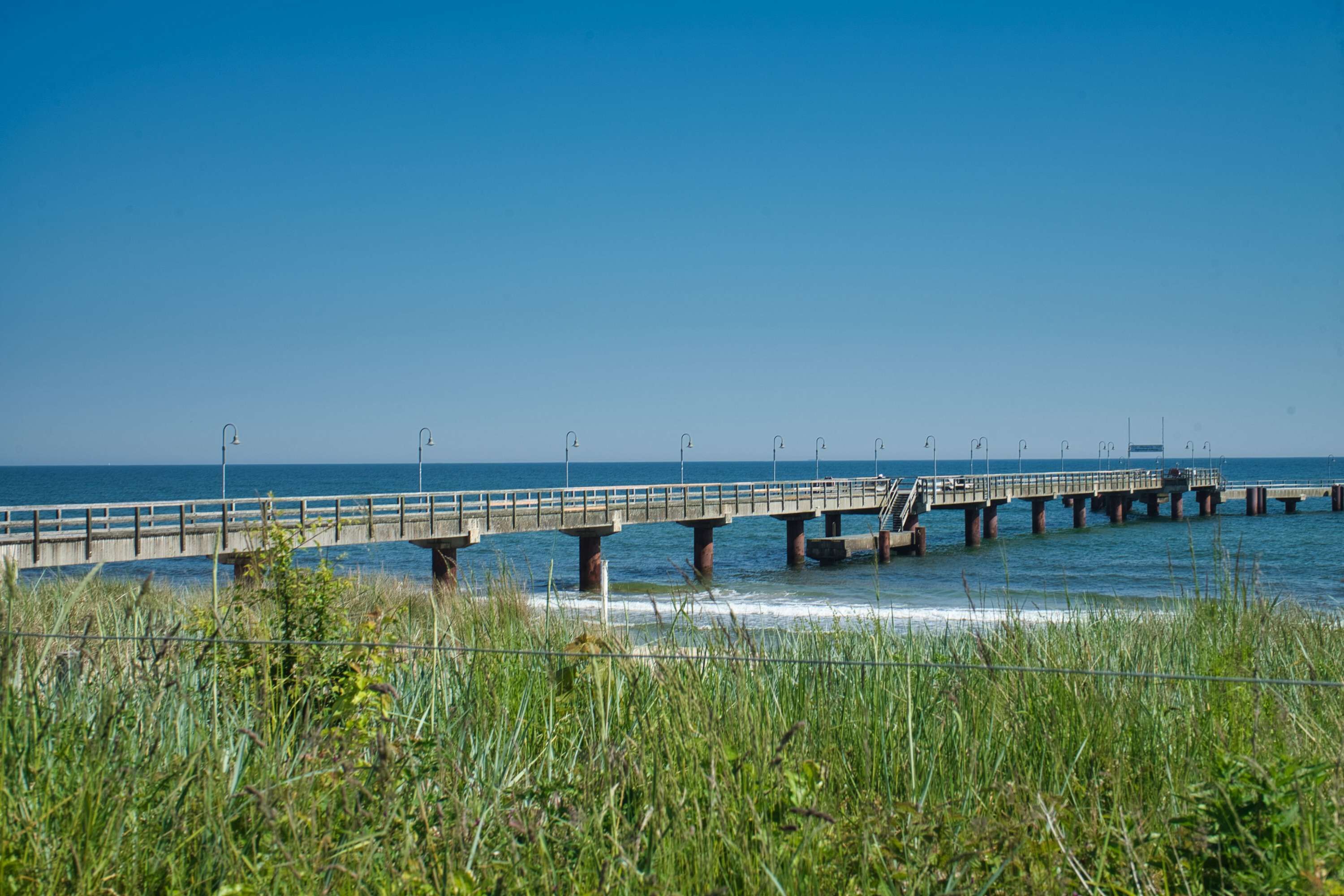 A pier extending into the water with a clear sky above.