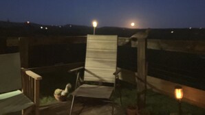 Een houten terras met een stoel en een kleine tafel, een houten hek en een lantaarnpaal.