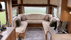 Een compleet ingerichte camper met een gezellige zithoek, een kitchenette en uitzicht op de natuur.