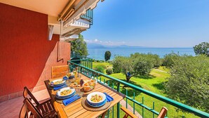 A wooden table set for a meal with a view of a lake and mountains. - San Sivino Apartment with pool by Wonderful Italy (Manerba del Garda)