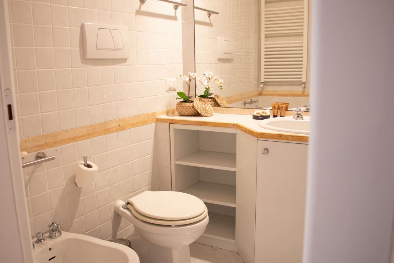 Un baño con azulejos blancos, encimera de madera, inodoro, bidé y espejo.