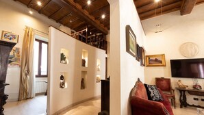 A spacious living area with a high ceiling, wooden beams, and a red sofa. - The Best Rent - Apartment in Piazza Venezia (Roma)