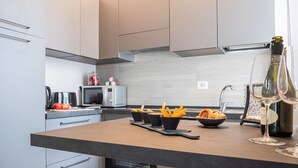 A modern kitchen with a dark countertop, a microwave, a kettle, and a wine bottle. - The Best Rent - Apartment in Milan downtown (Milano)