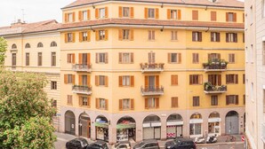 A multi-story yellow building with balconies, parked cars, and a tree in the foreground. - The Best Rent - Apartment in Milan downtown (Milano)