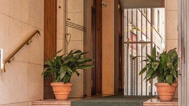 A marble staircase with a handrail, flanked by two potted plants, leading to a gated entrance. - The Best Rent - Apartment in Milan downtown (Milano)