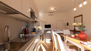 A modern kitchen with a sink, stove, and dining area with chairs and a table. - The Best Rent - Apartment near Isola Tiberina (Roma)