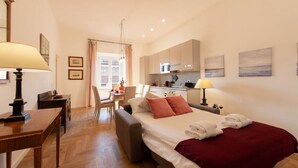 A compact hotel room with a bed, bedside table, lamp, and a view of the kitchen area. - The Best Rent - Apartment near Isola Tiberina (Roma)