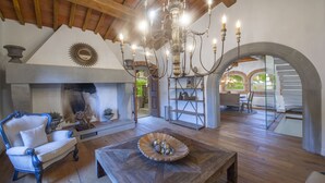 Un salon spacieux doté d’une cheminée, d’un lustre et d’une table basse en bois.