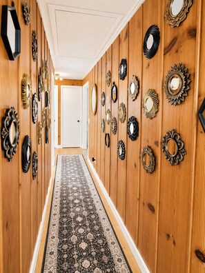 Un pasillo con paneles de madera y un tapete estampado, con varios espejos colocados en la pared.