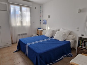 Une chambre à coucher avec un grand lit, une table de chevet, une commode, une armoire et une fenêtre avec des rideaux.