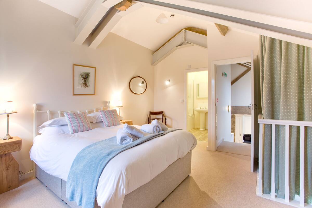 A bedroom with a large bed, bedside tables, a mirror, and a view of the bathroom.
