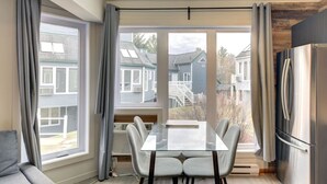 A modern kitchen with a large window, a dining table, and a built-in refrigerator. - Chouette Tremblant Ski In/Out Pedestrian Village (Mont Tremblant)