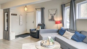 A modern living room with a grey sofa, a black armchair, and a coffee table with decorative items. - Chouette Tremblant Ski In/Out Pedestrian Village (Mont Tremblant)