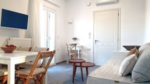 A compact living space with a dining area, a sofa, and a small table. - Modern 2bedroom apartment in the heart of Naxos, walking distance to the beach (Naxos)