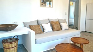 A modern living room with a sofa, a small table, a basket, and a framed picture on the wall. - Modern 2bedroom apartment in the heart of Naxos, walking distance to the beach (Naxos)