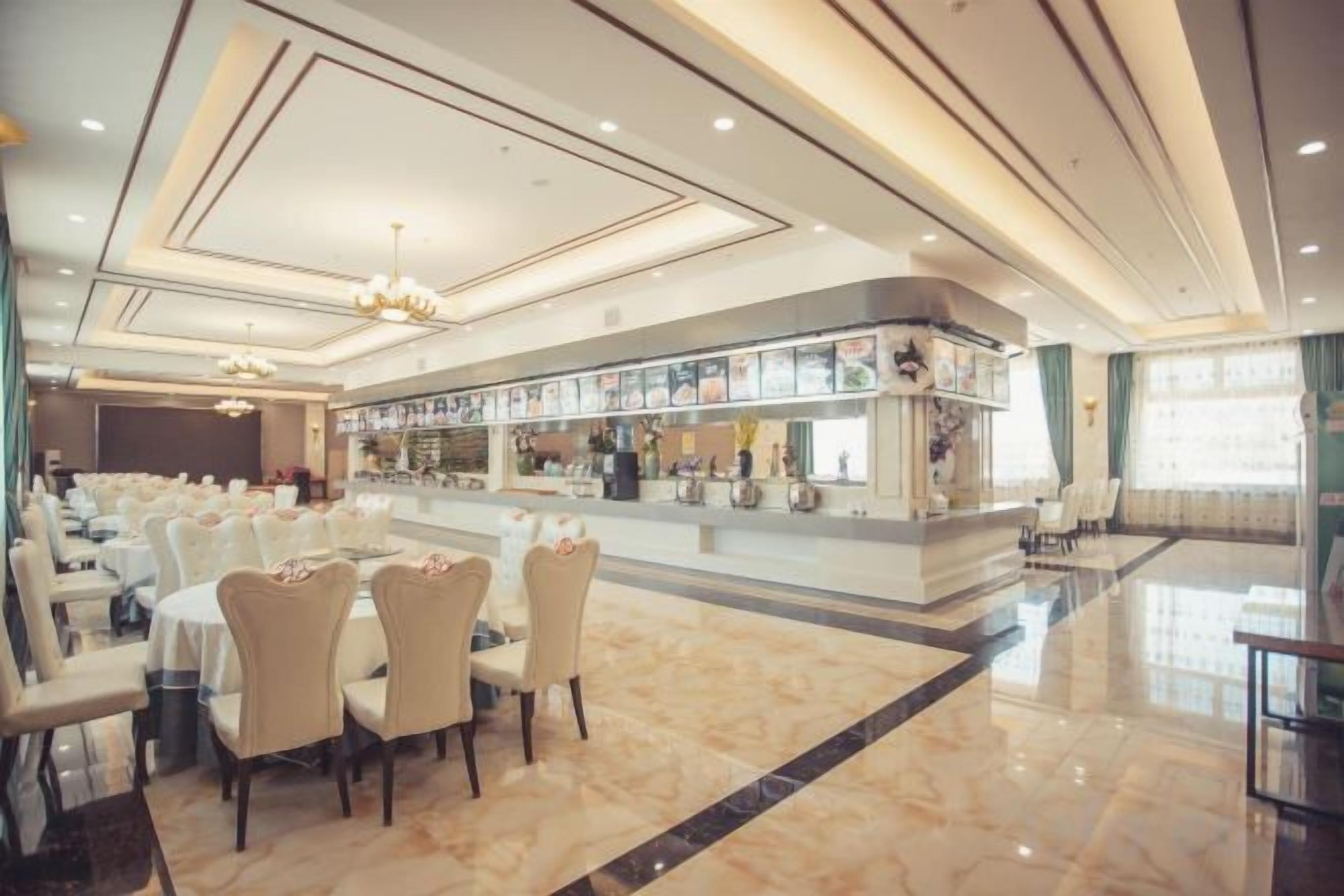 A hotel dining area with tables and chairs, a bar, and a polished floor.