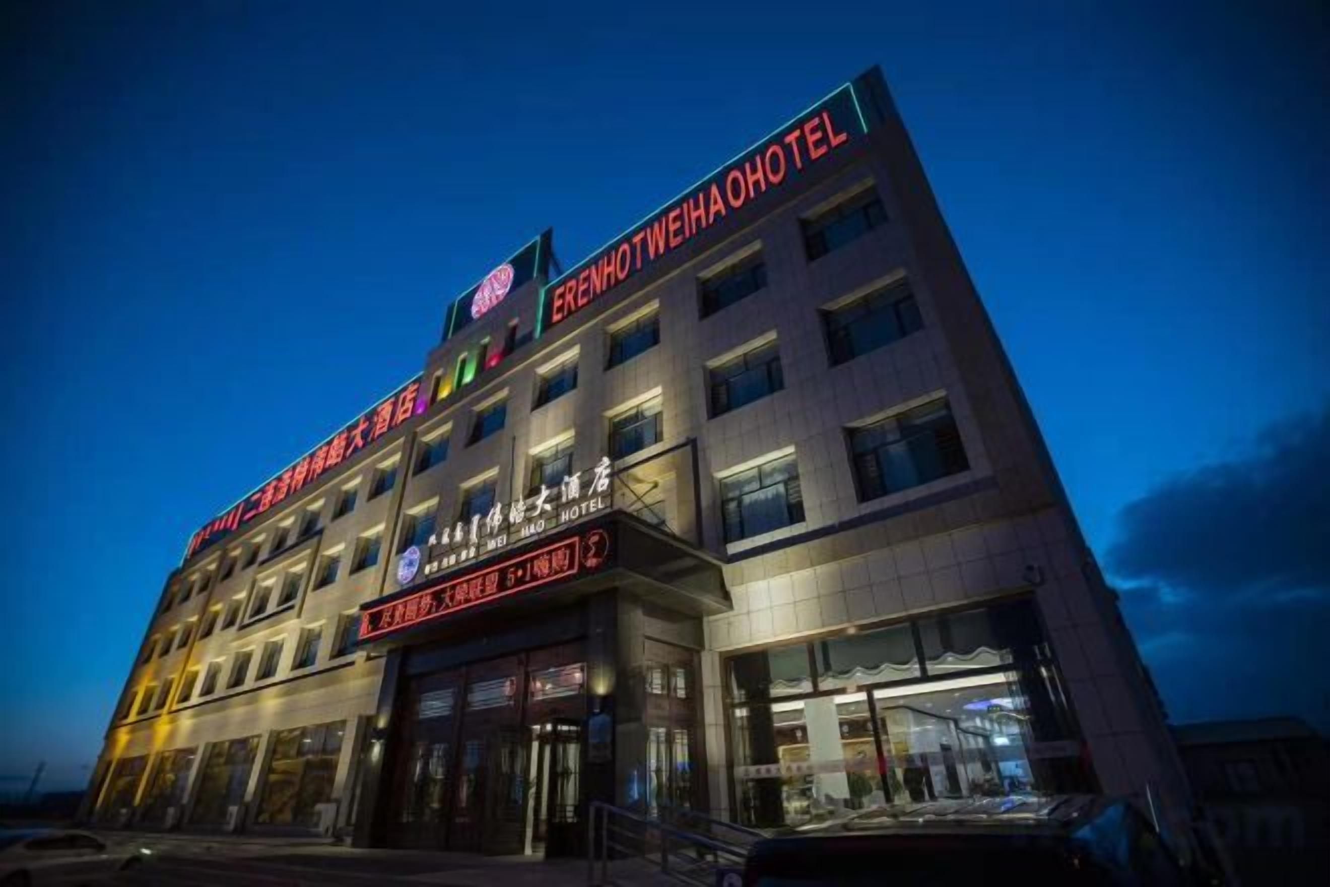 A hotel with multiple floors, a prominent sign, and a well-lit entrance.