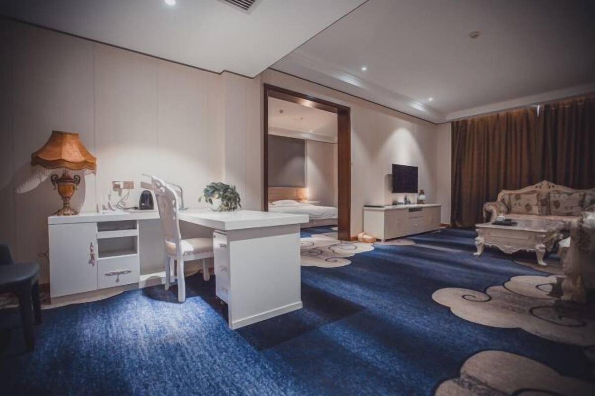 Une chambre d’hôtel équipée d’un bureau, d’une chaise, d’un lit, d’une télévision et d’un canapé.