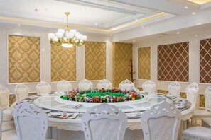 A formal dining room with a round table, white chairs, and a chandelier.