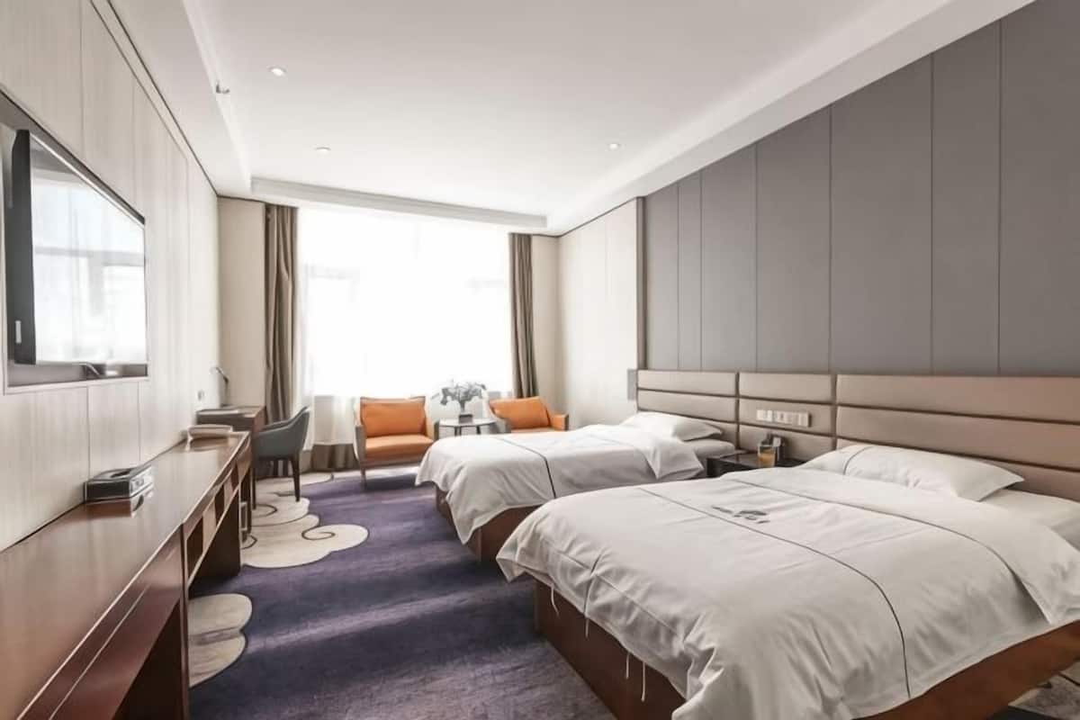 Une chambre d’hôtel avec deux lits, un bureau, une chaise et un téléviseur.