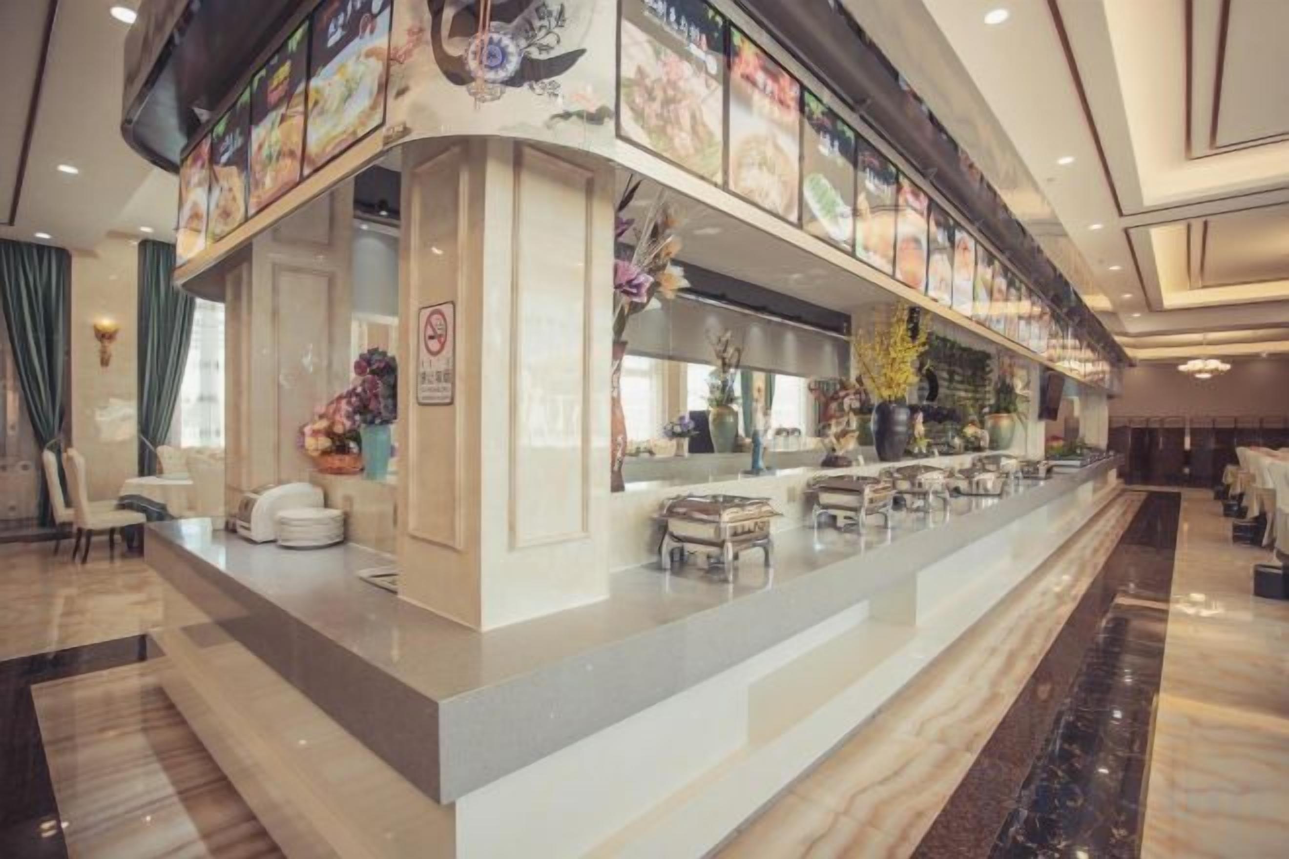 A hotel lobby with a long reception desk, a bar area, and seating arrangements.