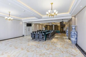 Un salón de conferencias con una larga mesa, sillas y una araña.