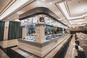 Un espace bar doté d’un comptoir incurvé, de sièges et offrant une vue sur le hall d’entrée.