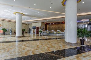 A spacious lobby with marble flooring, large columns, a reception desk, and potted plants. - Erenhot Weihao Hotel (Erenhot)