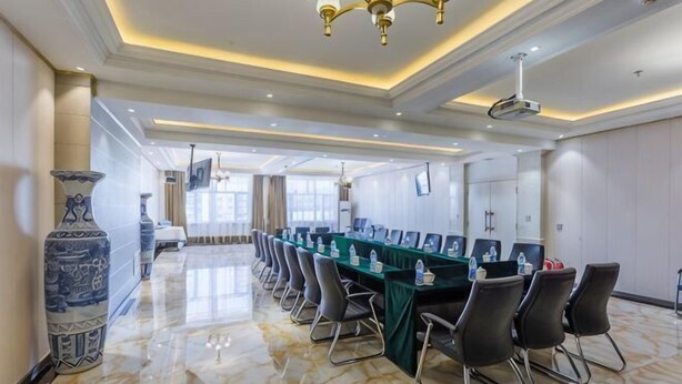 Une salle de conférence avec une longue table, des chaises et un lustre.