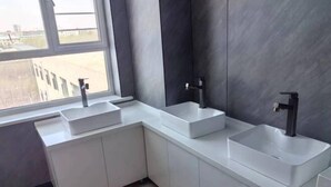Une salle de bain moderne avec deux lavabos, une fenêtre et une vue sur l’extérieur.
