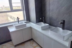 Une salle de bain moderne avec deux lavabos, une fenêtre et une vue sur l’extérieur.