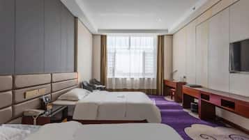 Habitación de hotel con dos camas, un escritorio, una silla, un televisor y un ventanal grande.