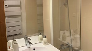 A bathroom with a white sink, a mirror, a glass-enclosed shower, and a towel rack. - Beautiful apartment with balcony and covered parking (Pralognan-la-Vanoise)