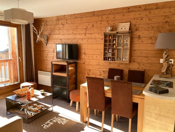 Ein gemütliches Blockhaus-Interieur mit Essbereich, Fernseher und einer Vitrine mit Dekoration.