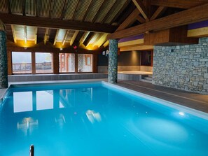 Ein großer, überdachter Schwimmbereich mit Steinwänden und Holzbalken.