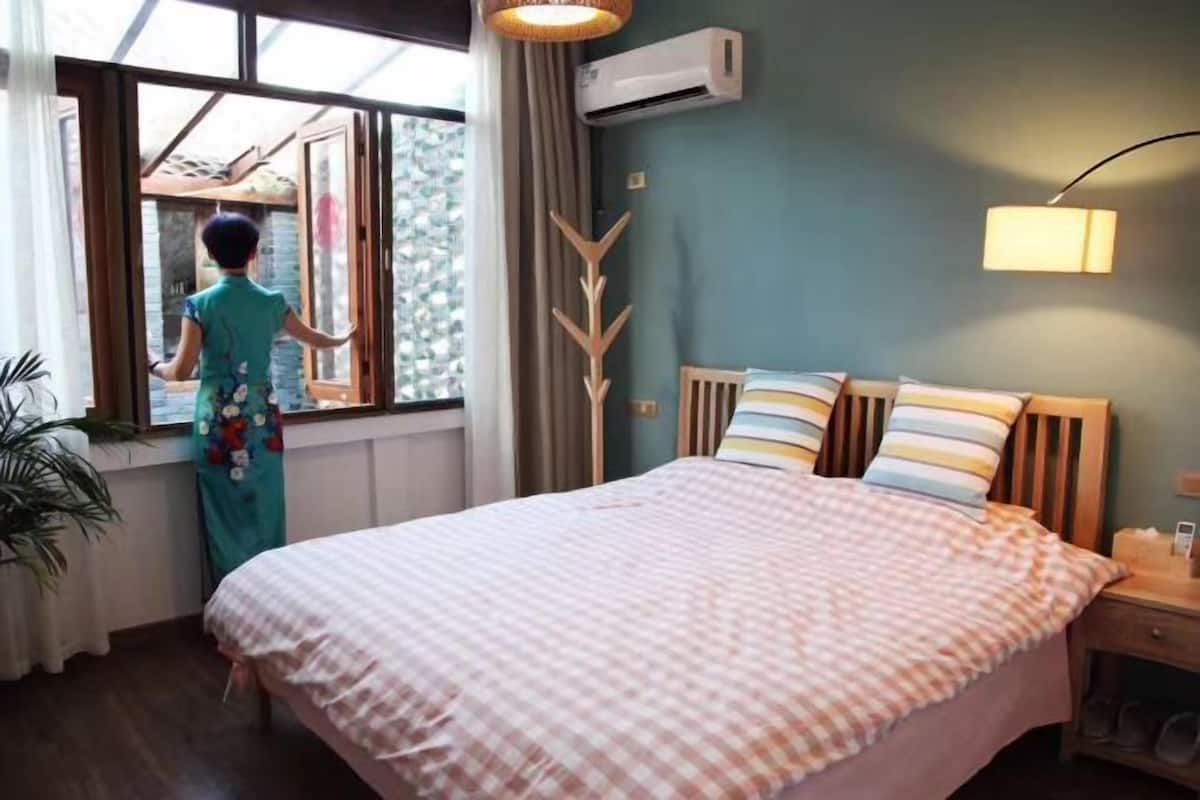 Um quarto com uma cama, janela, mesa de cabeceira e abajur.
