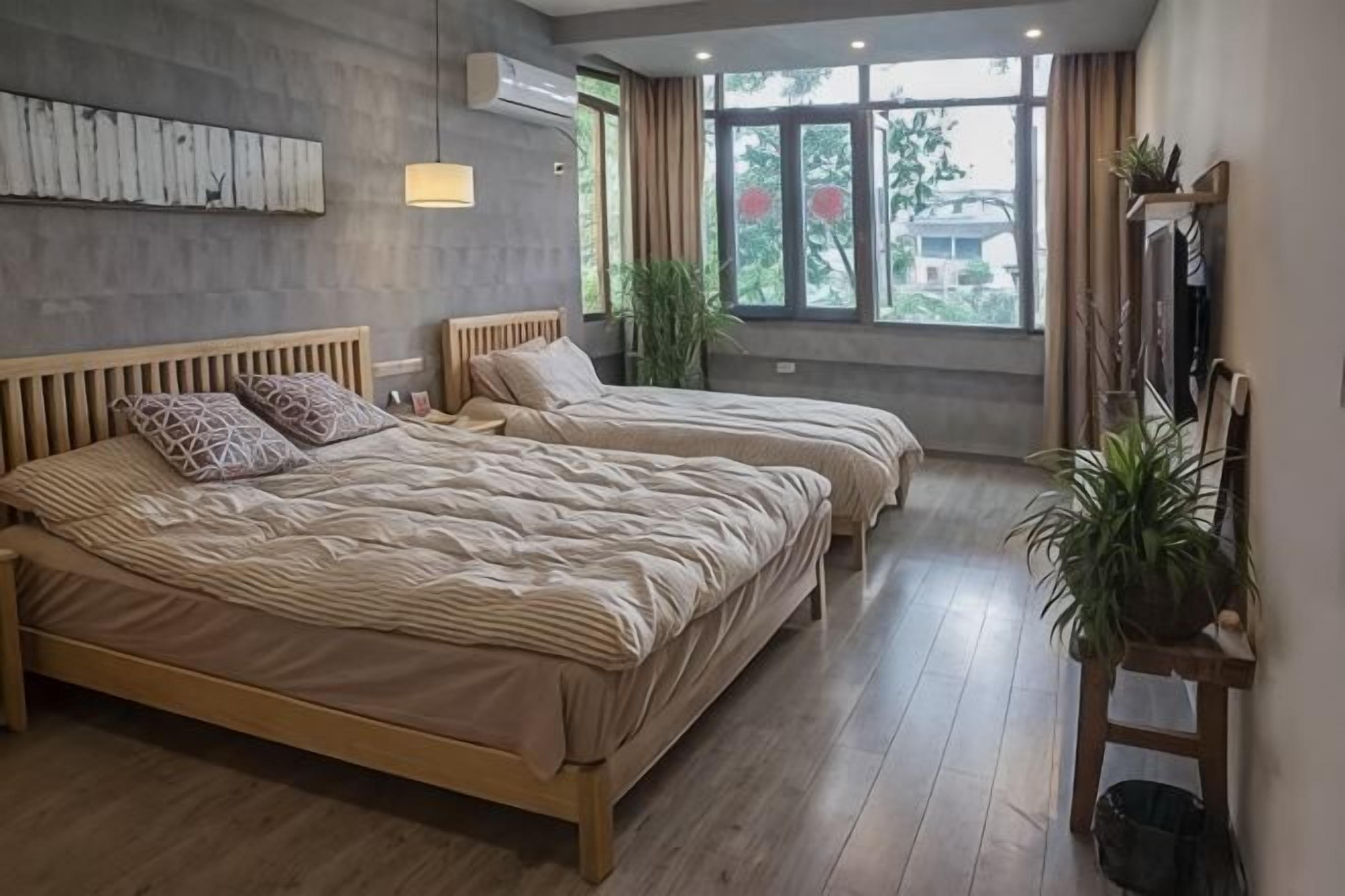 Une chambre avec deux lits, une grande fenêtre et une plante.