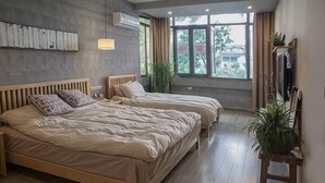 Un dormitorio con dos camas, un ventanal grande y una planta.