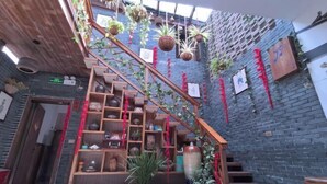 Una escalera con barandas de madera, rodeada de estantes con diversos objetos y plantas.
