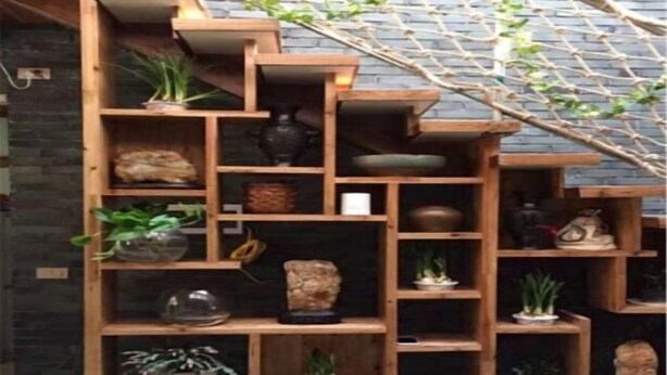 Una estantería de madera escalonada con varios objetos decorativos y plantas.