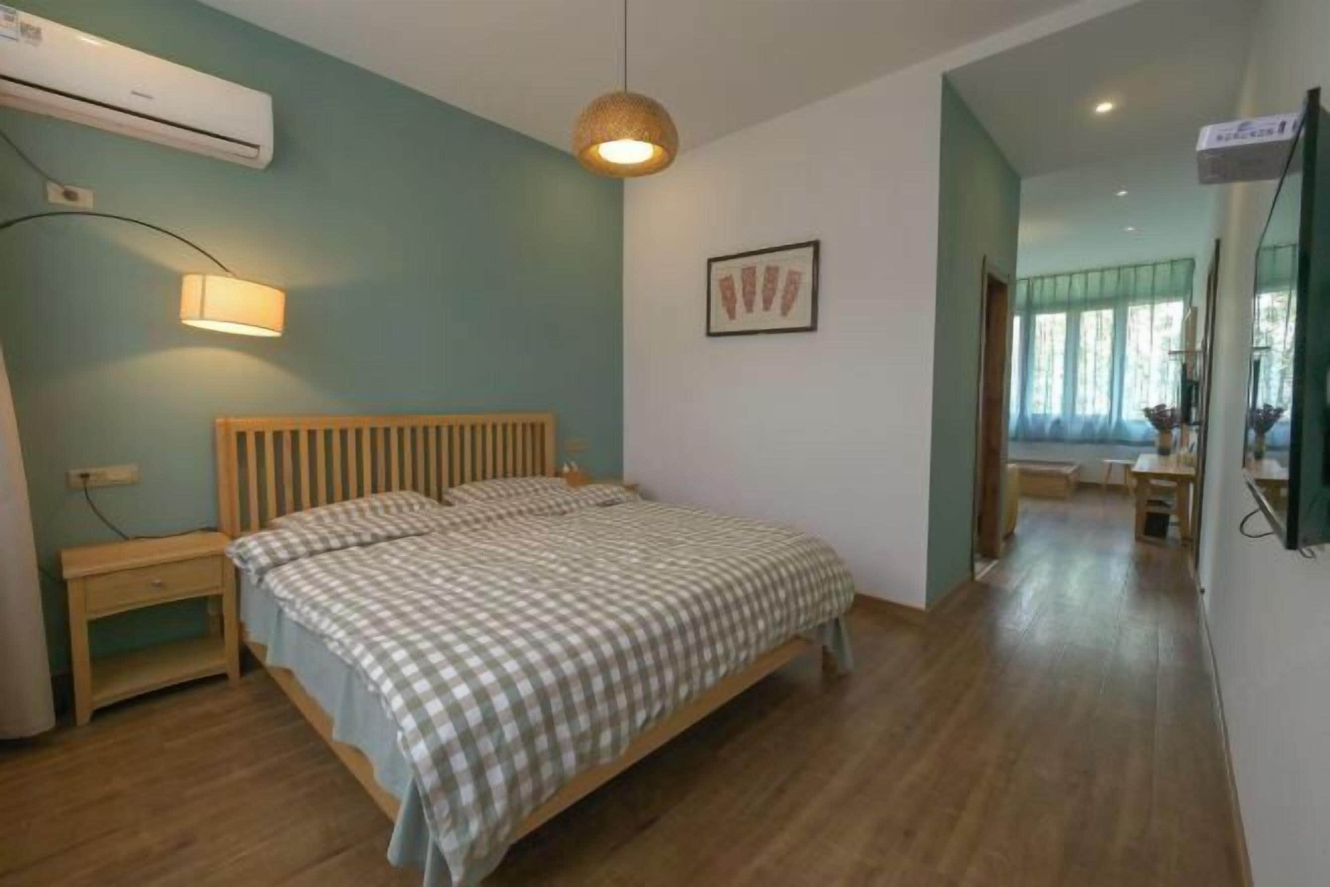 A bedroom with a bed, bedside table, lamp, and an air conditioning unit.
