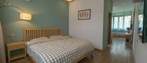 A bedroom with a bed, bedside table, lamp, and an air conditioning unit.