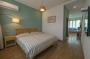 Un dormitorio con cama, mesita de noche, lámpara y un equipo de aire acondicionado.