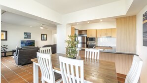 A modern kitchen with wooden cabinets, a stainless steel refrigerator, and a microwave. - Riverview Apartment 1 Block 1 (ILUKA)