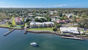 An aerial view of a coastal property with a marina, multiple buildings, and a large house with a prominent roof. - Riverview Apartment 1 Block 1 (ILUKA)