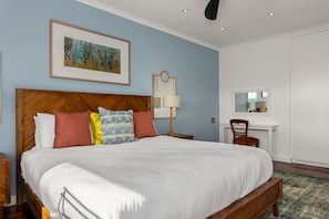 A neatly made bed with a wooden headboard, a bedside table, a lamp, and a chair. - Jagar Court 8 (Cape Town)